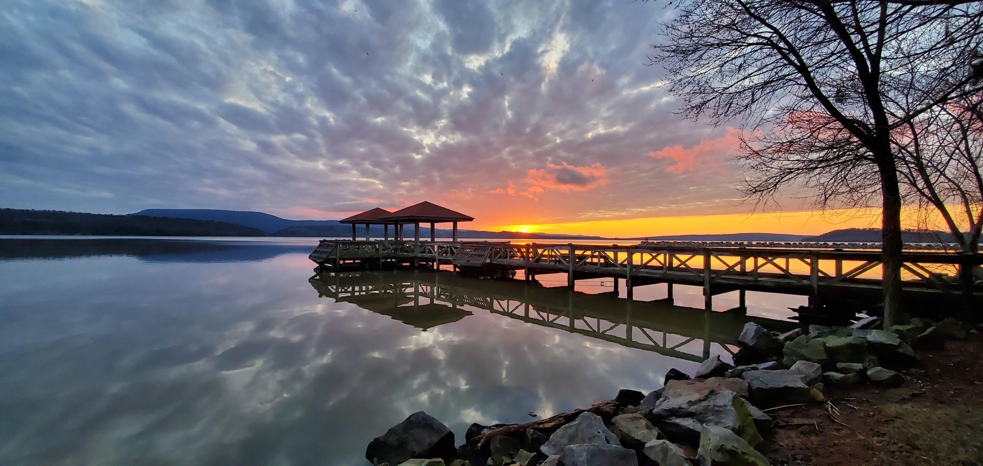 Sunset over the covered docks at Lake Dardanelle State Park, reflected in the still water